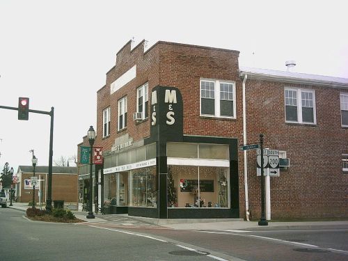 A brick building with "M&S" signage, featuring a storefront and traffic lights at a street intersection.