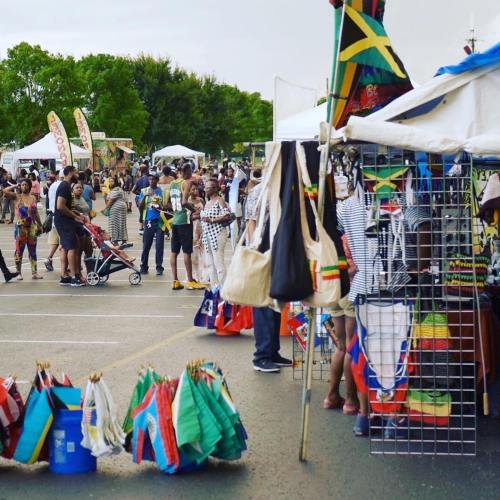 A vibrant outdoor market scene with colorful stalls, shoppers browsing, and a festive atmosphere.