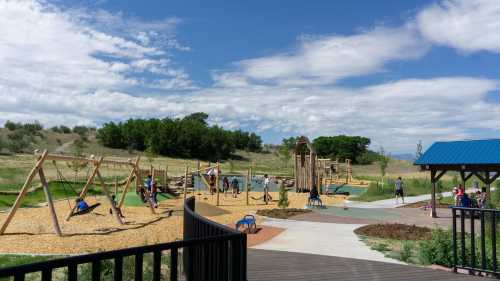 A sunny playground with swings, climbing structures, and children playing, surrounded by green hills and blue skies.