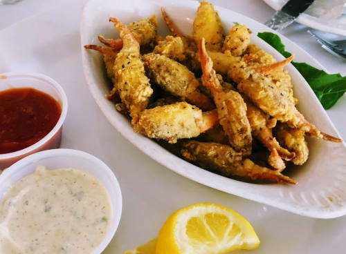 A plate of crispy fried soft-shell crabs served with dipping sauces and a lemon wedge.