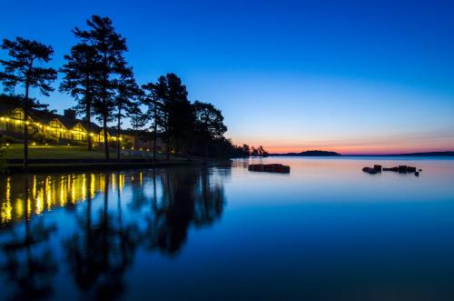A serene lake at dusk, reflecting trees and lights, with a gradient sky transitioning from blue to orange.