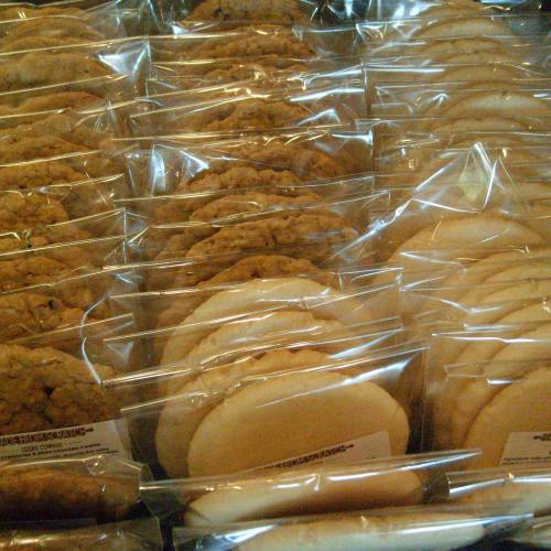 A display of assorted cookies neatly packaged in clear bags, arranged in rows.