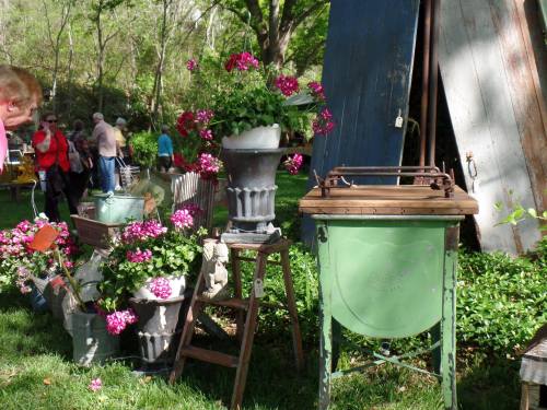 A garden scene featuring potted flowers, vintage decor, and a green washing machine on display.