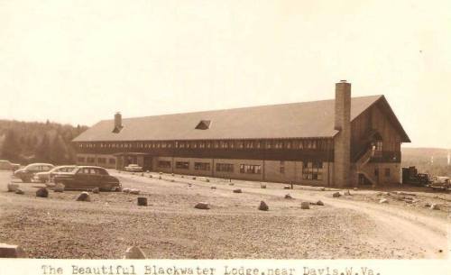Historic photo of Blackwater Lodge in West Virginia, featuring a large building and parked cars in a gravel lot.