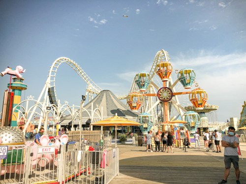A vibrant amusement park scene featuring a roller coaster, Ferris wheel, and visitors enjoying the attractions.