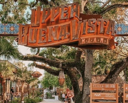 Colorful sign for Upper Buena Vista in Miami, surrounded by lush greenery and decorative elements.