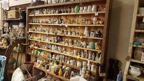 A wooden shelf filled with various colorful collectibles and figurines, neatly arranged with price tags.