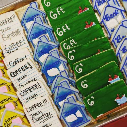A tray of decorated cookies featuring themes like "Zoom," "Coffee," and social distancing messages.