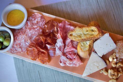 A wooden platter with assorted cured meats, cheeses, olives, bread, and a small bowl of dipping oil.