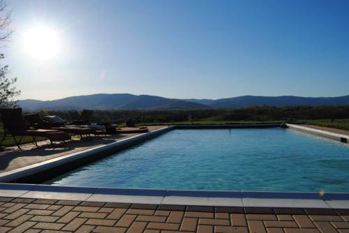 A serene pool with clear water, surrounded by lounge chairs and mountains under a bright blue sky.