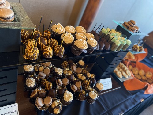 A display of assorted cupcakes, macarons, and desserts, decorated with chocolate and colorful frosting.