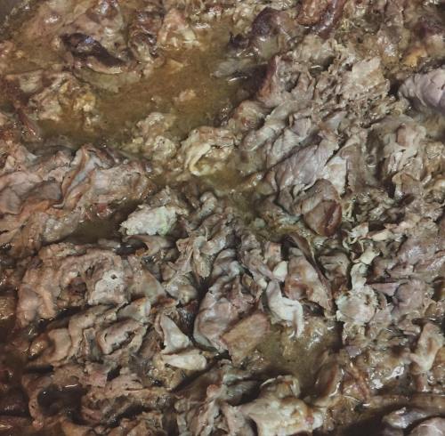 Close-up of cooked, shredded meat in a savory sauce, with a rich, brown color and a slightly glossy texture.