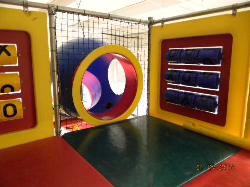 Colorful indoor play structure featuring tunnels, climbing areas, and interactive panels.