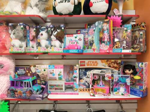 A colorful display of various toys, including plush animals, dolls, and LEGO sets, on a store shelf.