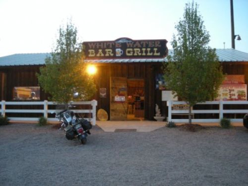 Exterior of White Water Bar & Grill, featuring a wooden facade, sign, and a motorcycle parked outside.