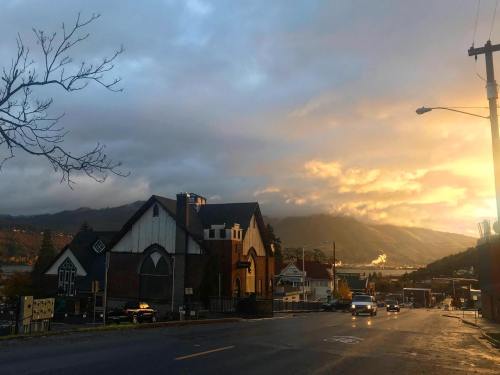 A scenic view of a town at sunset, with mountains in the background and a mix of buildings along the street.