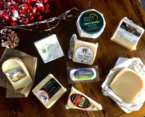 A variety of cheese blocks and wedges displayed on a wooden surface, surrounded by festive decorations.