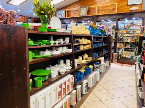 A store interior featuring shelves filled with colorful dishware and decorative items, with a warm wooden ambiance.