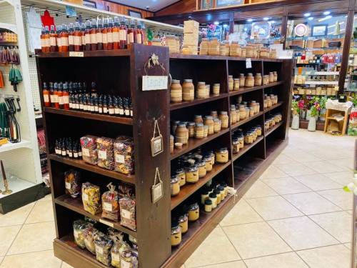 A wooden shelf filled with various candles and scented products in a cozy store setting.