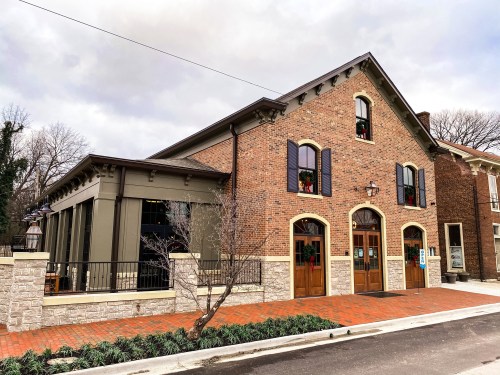 A charming brick building with festive decorations, featuring large windows and a welcoming entrance.