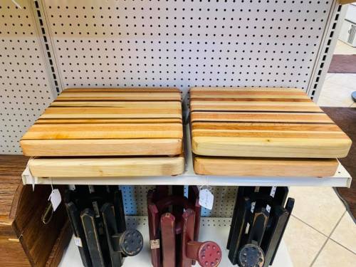 Two wooden cutting boards with striped designs, displayed on a shelf with other kitchen items.