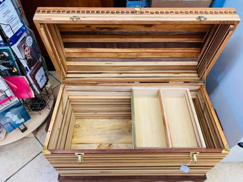 A wooden storage chest with a striped design, featuring a divided interior and an open lid.