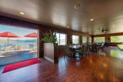 Interior of a restaurant with wooden decor, tables, and a view of a patio with umbrellas by the water.