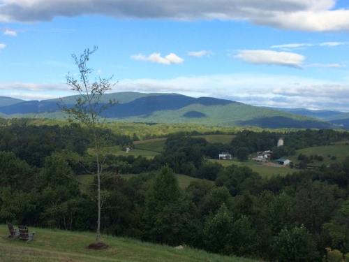 A scenic view of rolling green hills and mountains under a partly cloudy sky.
