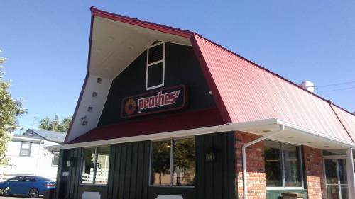 A building with a red roof and green walls featuring a sign that reads "Peaches." Clear blue sky in the background.