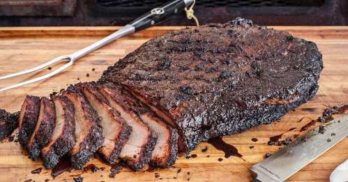 A perfectly smoked brisket on a wooden cutting board, sliced and ready to serve, with a carving knife nearby.