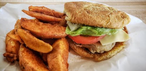 A delicious burger with lettuce, tomato, and cheese, served with crispy potato wedges on the side.
