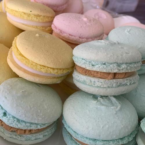 A colorful assortment of macarons in pastel shades of yellow, pink, and mint green, stacked on a plate.