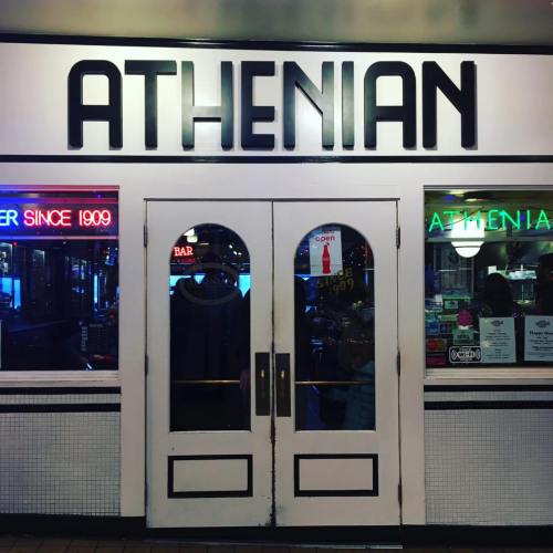 Entrance of the Athenian restaurant, featuring a sign and double doors with a "Open" sign visible.
