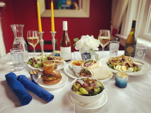 A beautifully set dining table with various dishes, wine, and candles, featuring burgers, salads, and wraps.