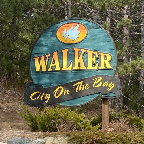 Sign for Walker, City on the Bay, featuring a green background with yellow lettering and a graphic of a state outline.