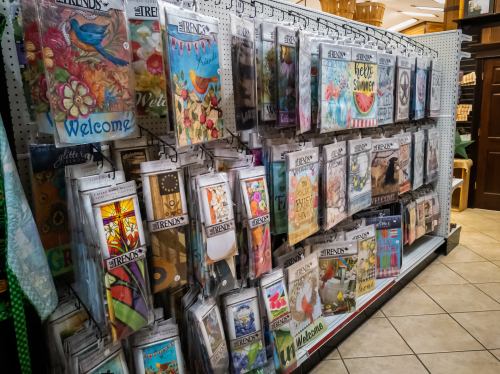 A display of colorful seasonal banners and flags hanging on a wall in a store.