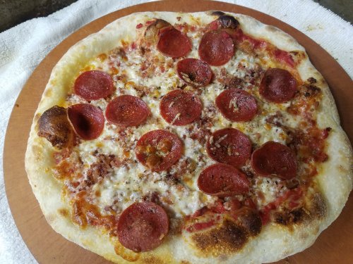 A freshly baked pepperoni pizza with melted cheese on a wooden pizza peel.