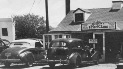 Black and white photo of Bigelow's Fried Clams, featuring vintage cars parked outside the restaurant.