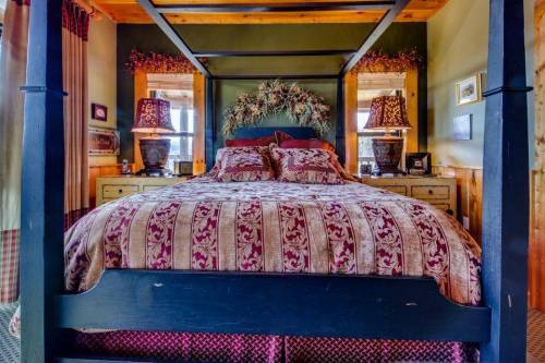 A cozy bedroom featuring a four-poster bed with patterned bedding, two lamps, and rustic decor.