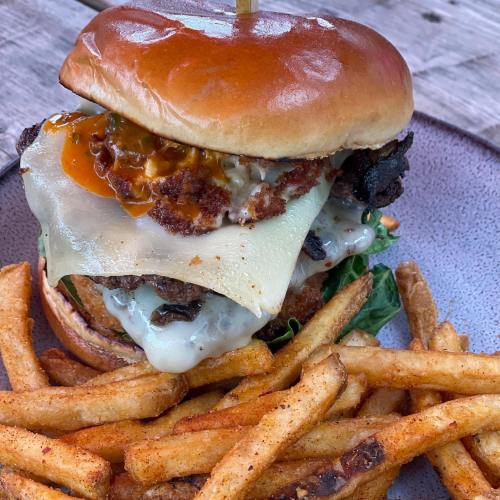 A juicy burger with melted cheese, crispy toppings, and a side of golden fries on a rustic plate.