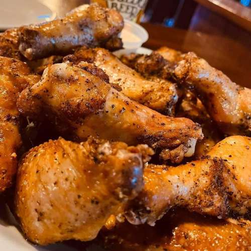 A close-up of a plate filled with seasoned, golden-brown chicken wings.