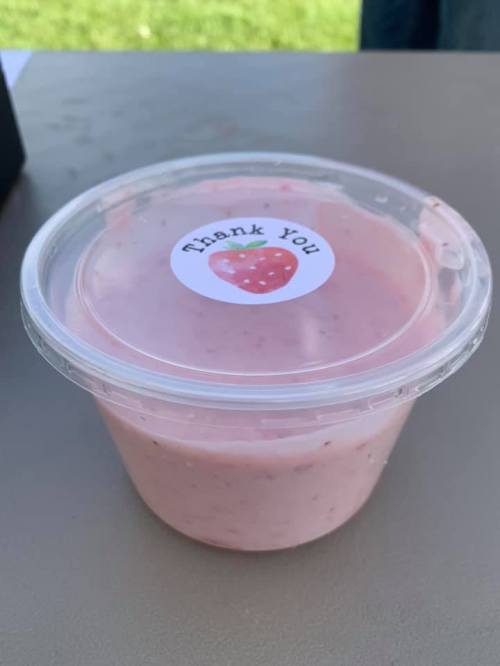 A clear container of pink yogurt or smoothie with a "Thank You" sticker featuring a strawberry on top.