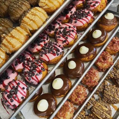 A variety of colorful donuts arranged on trays, featuring sprinkles, icing, and different toppings.