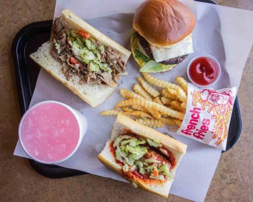 A tray with a burger, two sandwiches, crinkle-cut fries, and a pink drink.