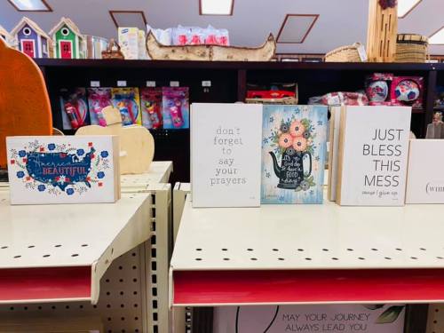 A display of decorative signs with inspirational messages on a shelf in a store.