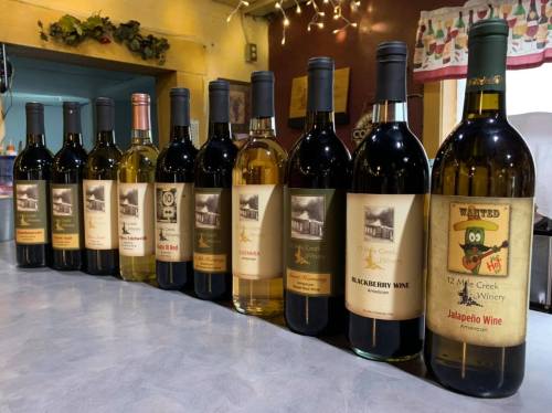 A row of various wine bottles on a table, each with unique labels showcasing different types of wine.