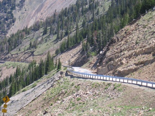 Winding road through a mountainous landscape with trees and rocky terrain.