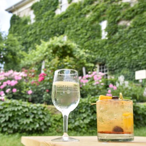 A refreshing cocktail sits on a wooden table, surrounded by lush greenery and blooming flowers in the background.