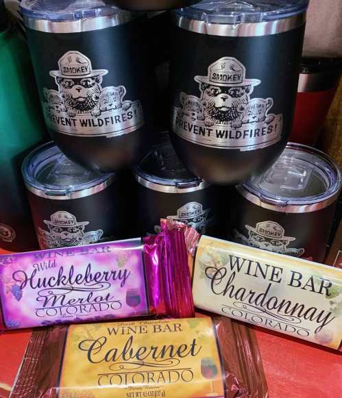 A collection of wine-themed items, including cups and chocolate bars, featuring flavors like huckleberry and chardonnay.
