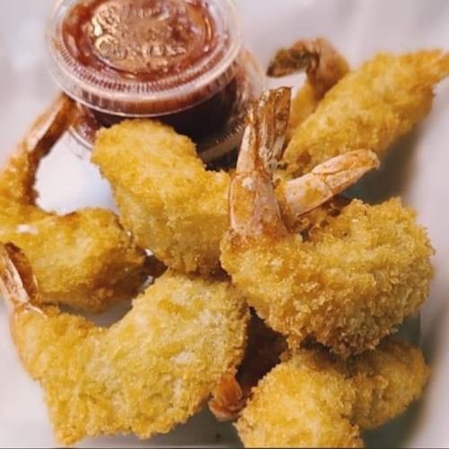 Crispy fried shrimp served with a small container of dipping sauce on a white plate.
